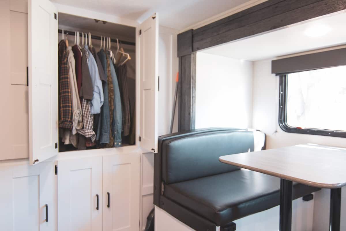 Wardrobe with hanging clothes and cabinets in the Houston Camper