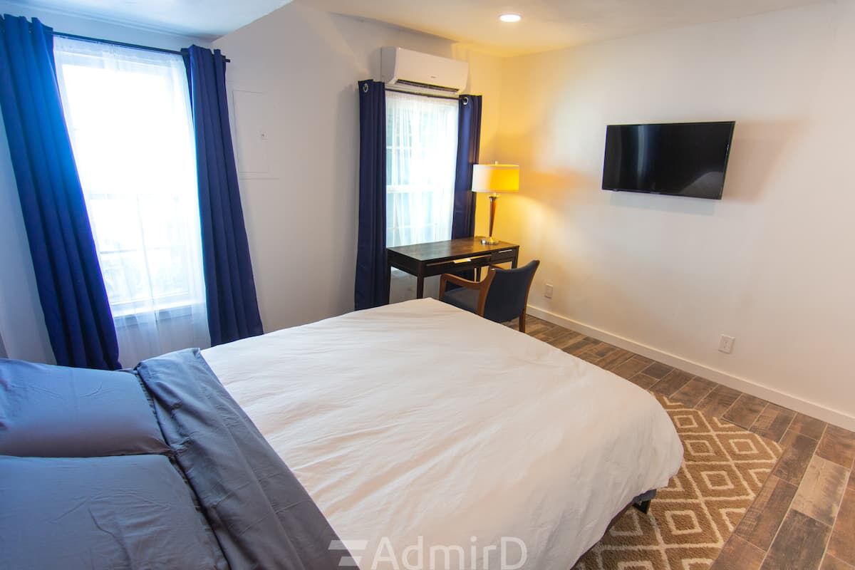 Bedroom with a wall-mounted TV and a desk by the window