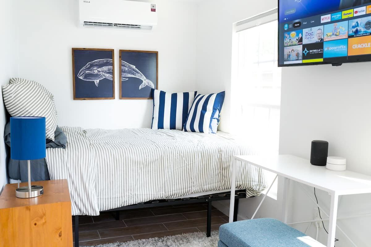 Bed with striped linens, blue pillows and a framed whale print