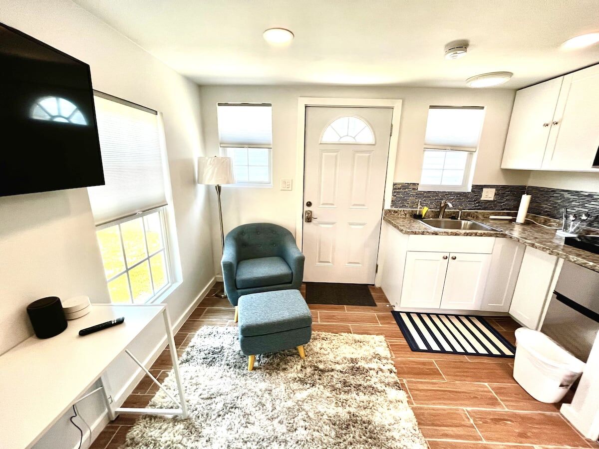 Bright studio with a blue accent chair, a white door and a kitchenette