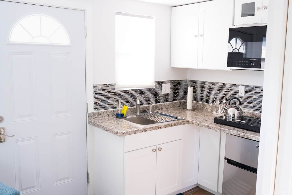 Kitchenette with white cabinets, a mosaic backsplash and a compact refrigerator