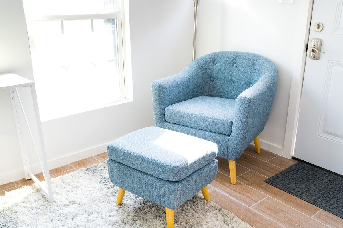 Blue accent chair and ottoman by the window