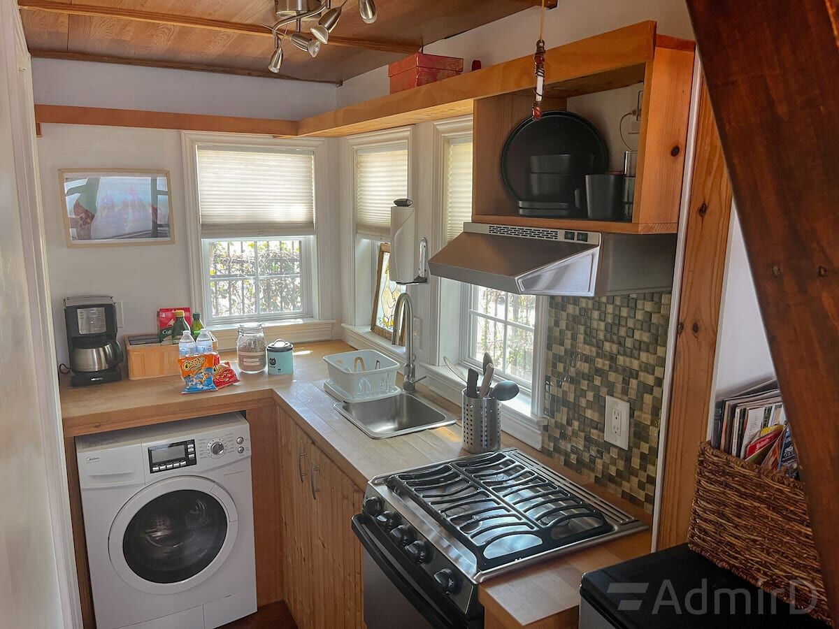 Compact kitchen with a sink, gas range and washer in the Houston Tiny House