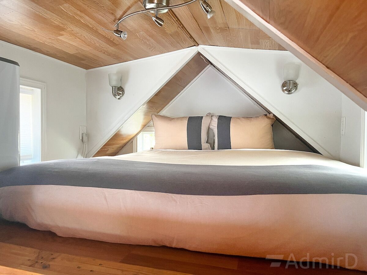 Loft bed with a pitched wood ceiling in the Houston Tiny House