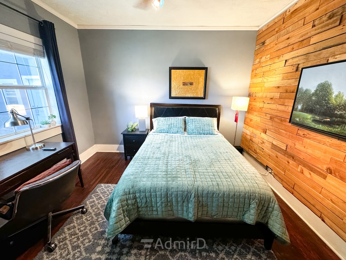 Queen bed, bedside lamp and desk by the window in the Midtown bedroom
