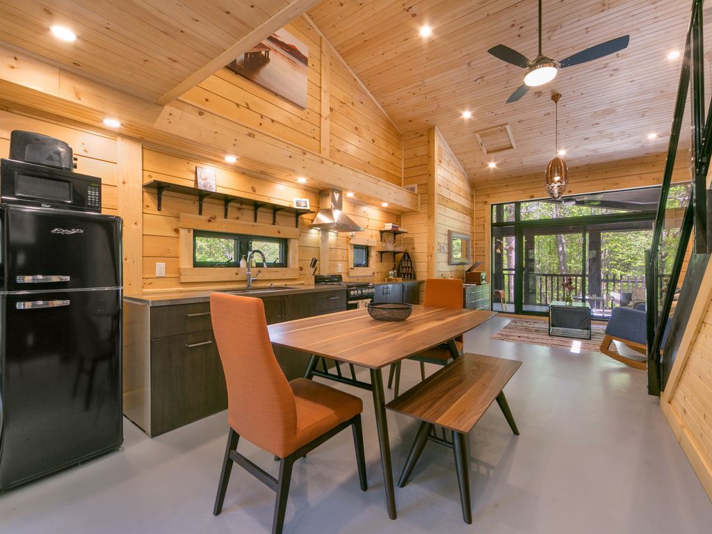 Open-plan kitchen and dining area in the Houston Tiny House, with wood-paneled walls and a vaulted ceiling